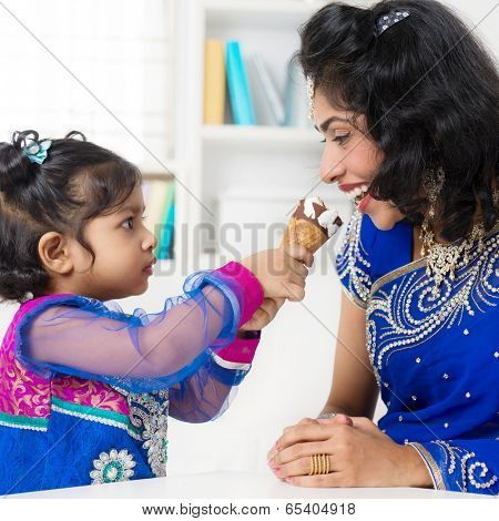 Indian girl feeding her mum ice-cream. Asian family living lifestyle at home.