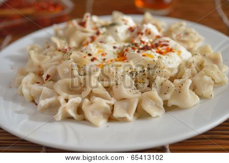 Turkish dumplings manti with strained yogurt and Aleppo pepper closeup