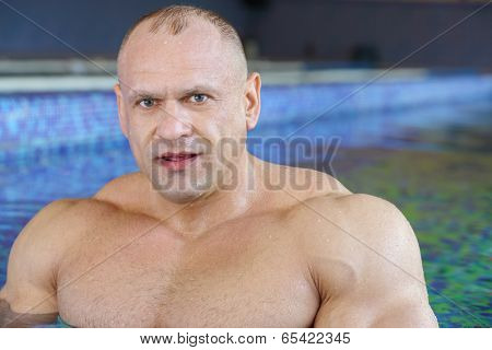 Close up of middle-aged bodybuilder standing in swimming pool 