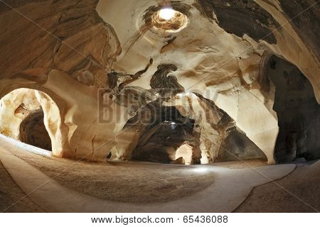 Israel National Park. Bell caves of Beit Guvrin.  Picturesque clay arches illuminated by the sun from the hole at the top and side entrances