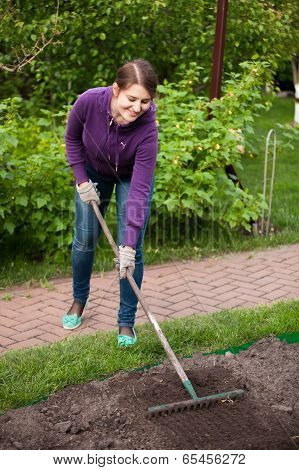 Beautiful Woman Working With Rake On Garden Bed