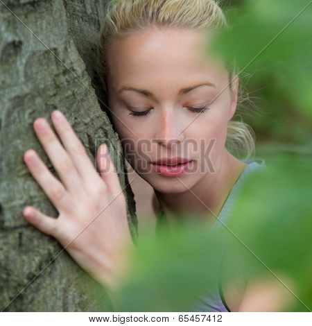 Young woman hugging a tree.