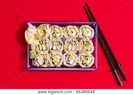 To Go Sushi Box On Red Table Cloth With Chopsticks