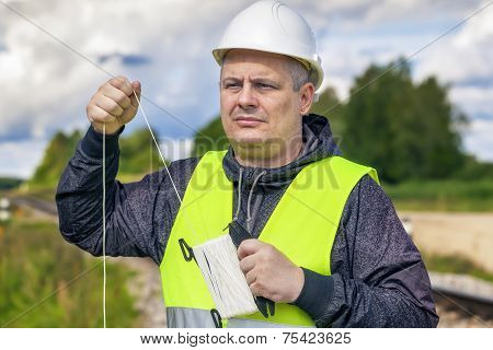 Railroad maitenence worker with rope near railway