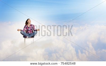 Young woman sitting on chair and meditating