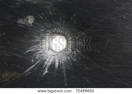 Bullet hole in thick sheet metal from the front view