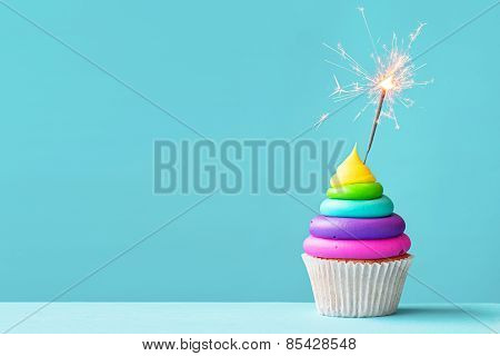 Brightly colored cupcake decorated with a sparkler