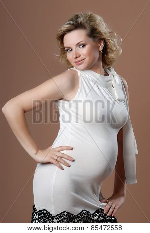 Smiling pregnant woman against beige background.