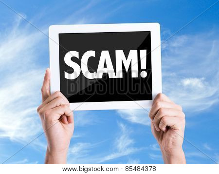 Tablet pc with text Scam! with sky background