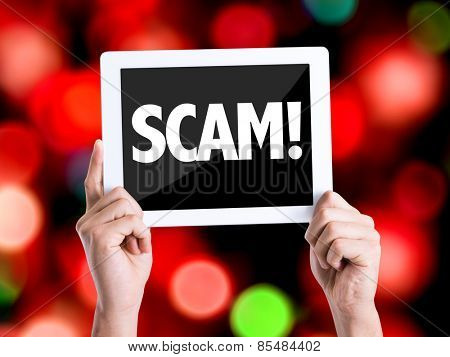 Tablet pc with text Scam! with bokeh background