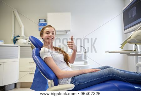 people, medicine, stomatology and health care concept - happy patient girl showing thumbs up at dental clinic office