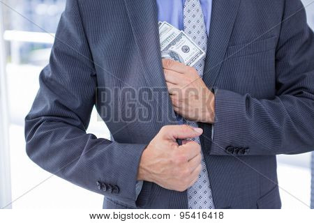 Dodgy businessman pocketing a bundle of dollar bills