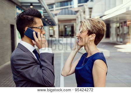 Business people standing in stret with their mobiles