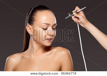 visagist making makeup for model with aerograph