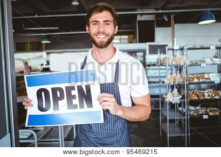 Smiling worker putting up open sign at the bakery