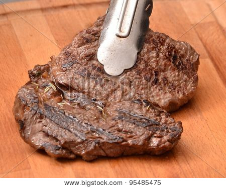 Holding grilled beef steak with a clip.