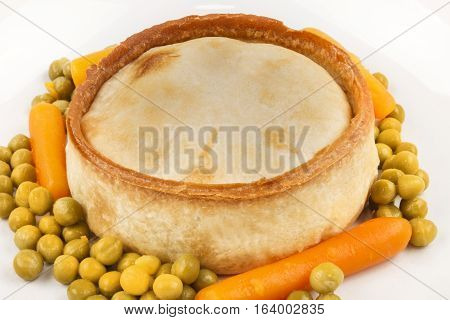 fresh baked scottish pie with carrot and pea on a plate