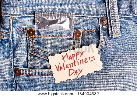 Valentine's Day card and condom. Greeting card on denim. Be safe while celebrate.