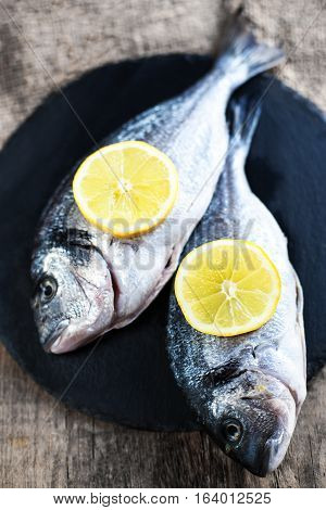 Fresh raw Dorado sea fish on wooden board with lemon and salt. Top view