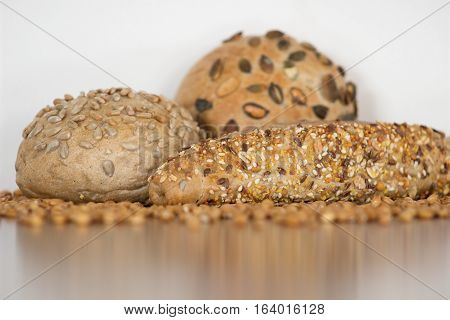 Three cereal delicious freshly baked baguettes with sunflower pumpkin sesame seeds and sprouted wheat grains around with white background.