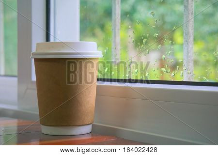 Paper coffee cup placed near the window.