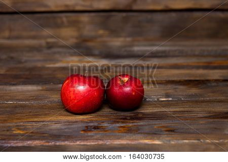 Two red ripe apples on a wooden background close up