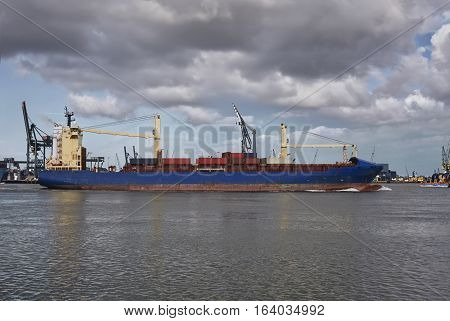 Panoramic image of a container ship passing cranes in Rotterdam harbor. The Netherlands