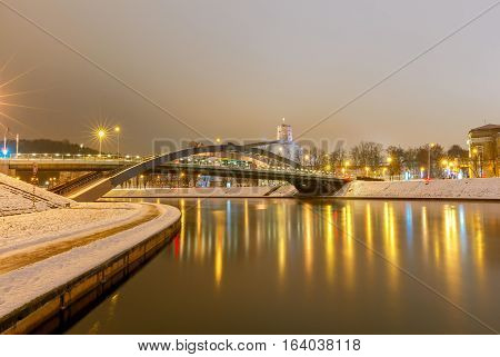 Iron arched Mindaugas Bridge across Neris River in Vilnius with night lighting. Lithuania.