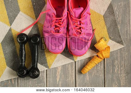 Trainers, dumbbells, ribbon, mat on floor. Stock photo Sporty mock up