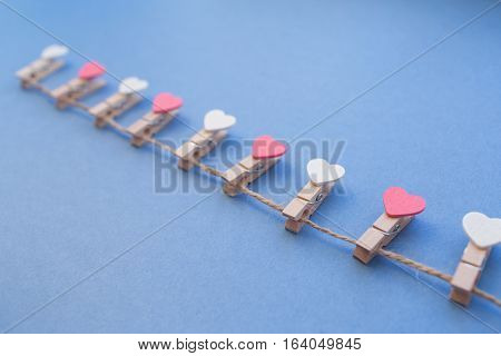 Clothespins with hearts with the twine lay a blue background