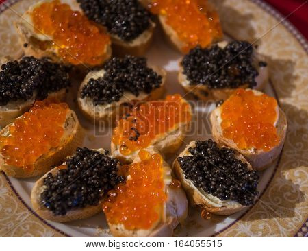 Plate with sandwiches with red and black caviar as one of the traditional components of russian new year celebration menu