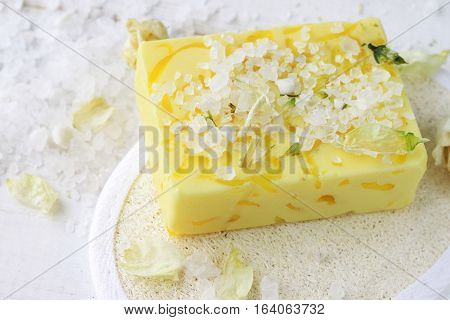 Bar of handmade bright yellow soap with sea salt, herbs, loofah.