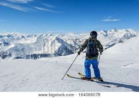 Back view of skier standing in front of snowy mountains