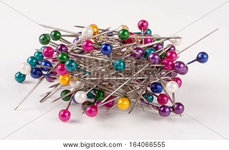 pile of of multi-colored sewing pins on a white background.