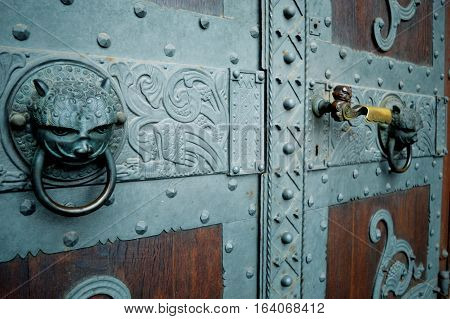 Rustic wooden door with bronze decoration and handle.