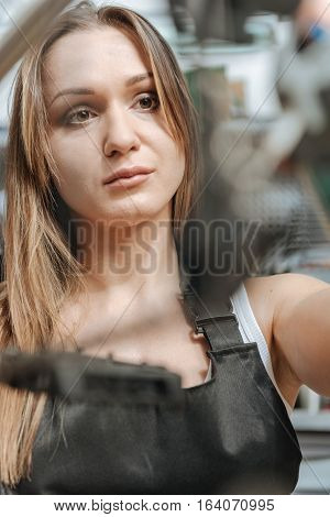 Attentive craftswoman. Athletic involved masterful craftswoman standing in the repair shop near the bicycle and working while repairing it