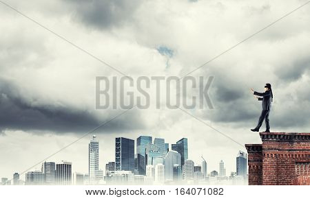 Businessman with blindfolder on eyes walking on building top