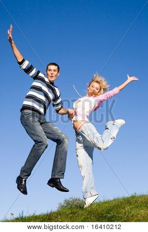Счастливые молодые любят пара - прыжки под голубым небом