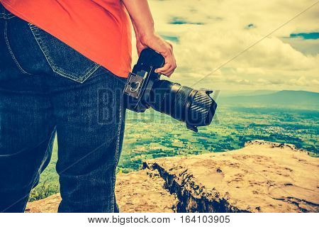 Woman with digital camera at view point on mountain. Outdoor at the daytime on summer day. Travel lifestyle vacations concept. Cross process and vintage tone effect.