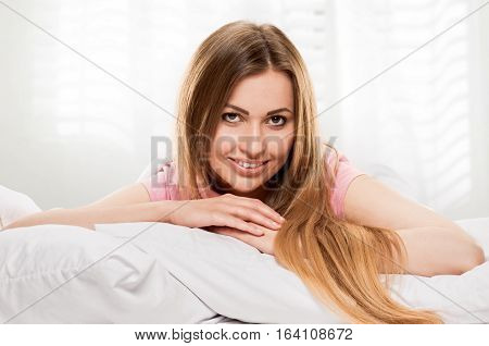 young woman laying in bedroom at early morning, on lightgray window background