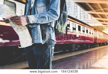 Backpacker Waiting For Long Journey Travel At Train Station With Backpack And Map On Hand. Travel Co