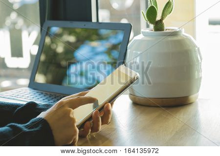 Businesswoman working with modern devices laptop computer and mobile phone in coffee shopwoman's hands using smart phone in interior woman at her workplace using technology .