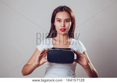 Attractive woman wearing virtual reality goggles. VR headset. Virtual reality concept on grey background.