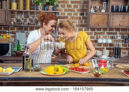 Mother and daughter cooking vegetable salad together