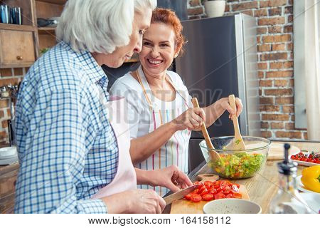 Smiling women in aprons cooking together in kitchen