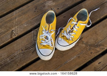 Cool teenager yellow sneakers on wooden background