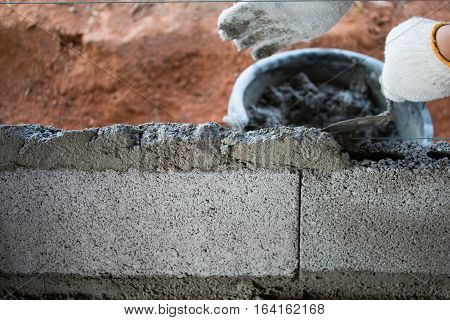 Bricklayer putting down another row of bricks in site