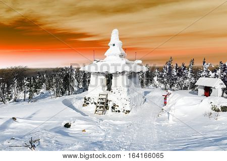 Snow covered Buddhist stupa on a mountaintop.