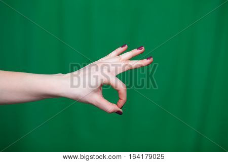 Female Hand shows ok fingers closeup on a green background