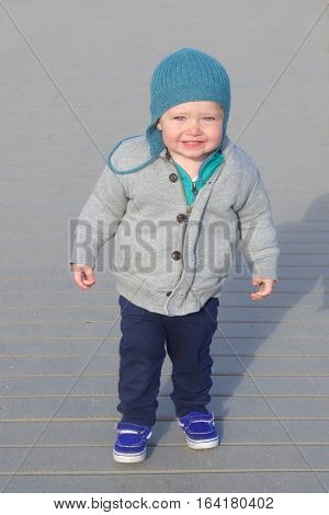 Adorable toddler boy shivering standing in sweatshirt and winter hat